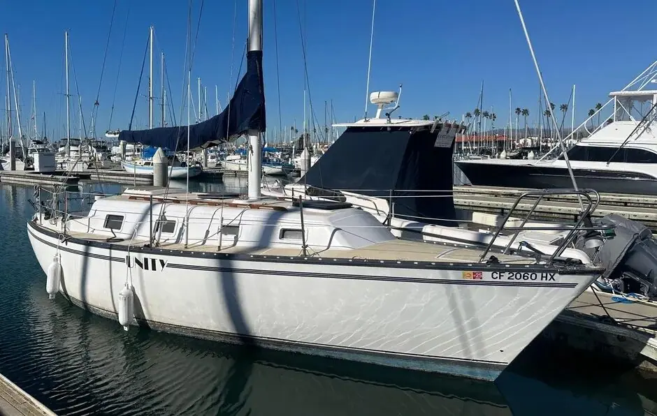 1979 Hunter 30 at a marina slip with a blue sail cover and dodger