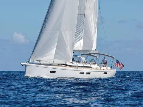 Hylas H60 sailing upwind under full sail with a crew member aft beside the flag