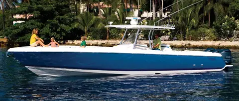 Intrepid 400 Center Console idling in profile near a palm lined shore with guests on the bow