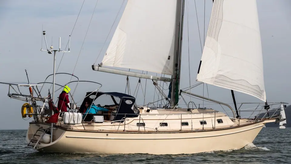 Island Packet 380 under sail seen from the quarter with crew in the cockpit behind the sprayhood