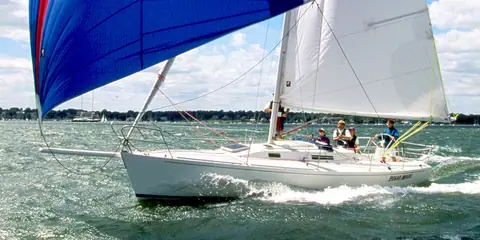 J/105 sailing downwind under a blue asymmetric spinnaker with crew in the cockpit