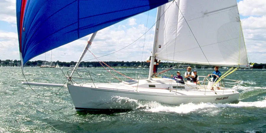J/105 sailing downwind under a blue asymmetric spinnaker with crew in the cockpit