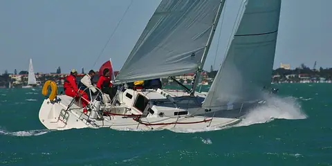 J/105 racing upwind with crew hiking on the rail and the open cockpit in view