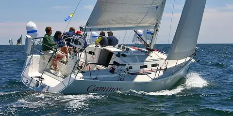 J/109 heeled upwind with the crew seated around the cockpit and wheel