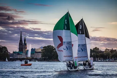 J/70s under spinnaker on the Alster with the Hamburg skyline