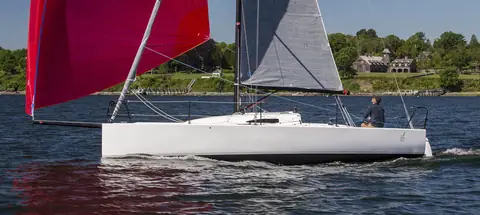 J/88 reaching under a red asymmetric spinnaker set from its bowsprit