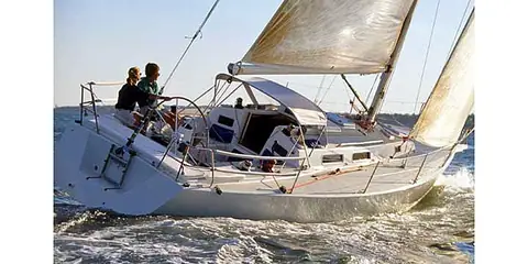 J/120 heeled upwind with two people at the wheel in the cockpit