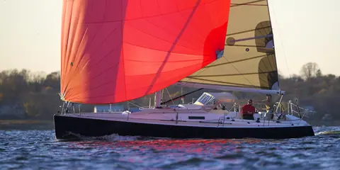 J/124 reaching under a red asymmetric spinnaker at sunset
