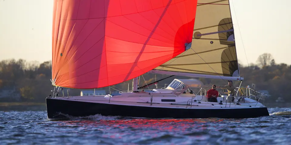 J/124 reaching under a red asymmetric spinnaker at sunset
