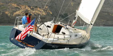 J/124 seen from astern with a couple in the cockpit and the flag flying