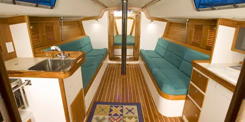 J/124 main saloon with green settees, teak joinery and the galley sink