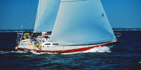 J/30 with a red boot stripe sailing under main and genoa with crew in the cockpit