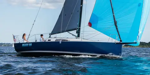 Navy blue J/99 reaching under a light blue asymmetric spinnaker
