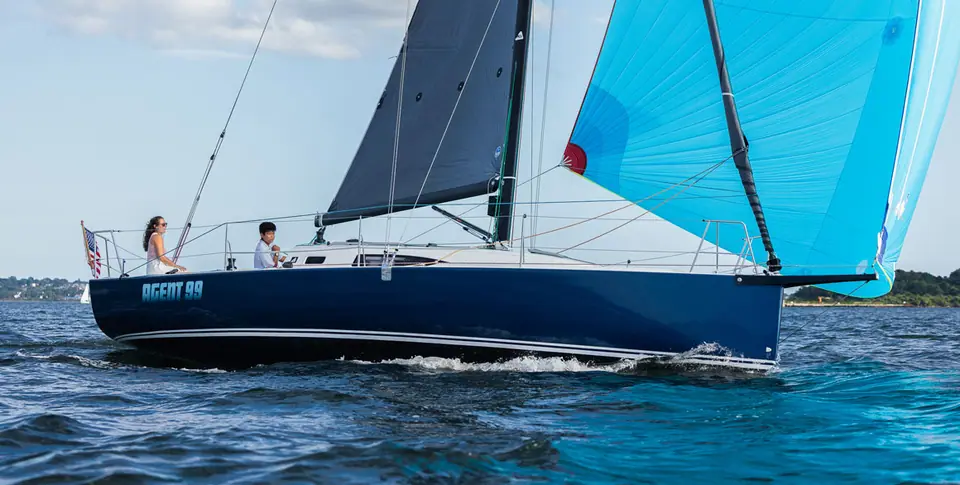 Navy blue J/99 reaching under a light blue asymmetric spinnaker