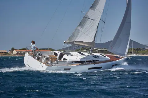 Jeanneau Sun Odyssey 440 heeled upwind showing its flush teak deck and twin wheels