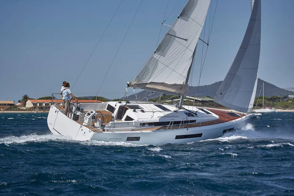 Jeanneau Sun Odyssey 440 heeled upwind showing its flush teak deck and twin wheels