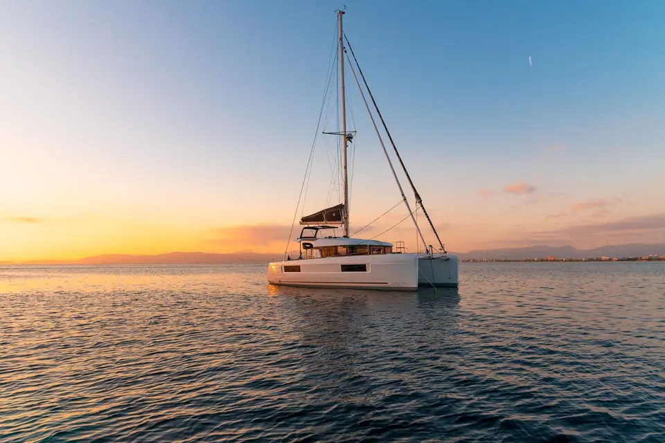 Lagoon 40 at anchor on calm water at sunset with its bimini covered helm station