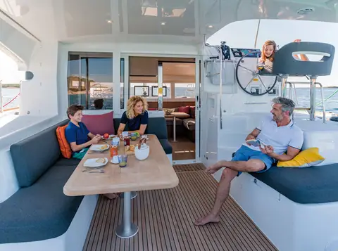 Lagoon 40 aft cockpit with a family at the teak table and the raised helm behind