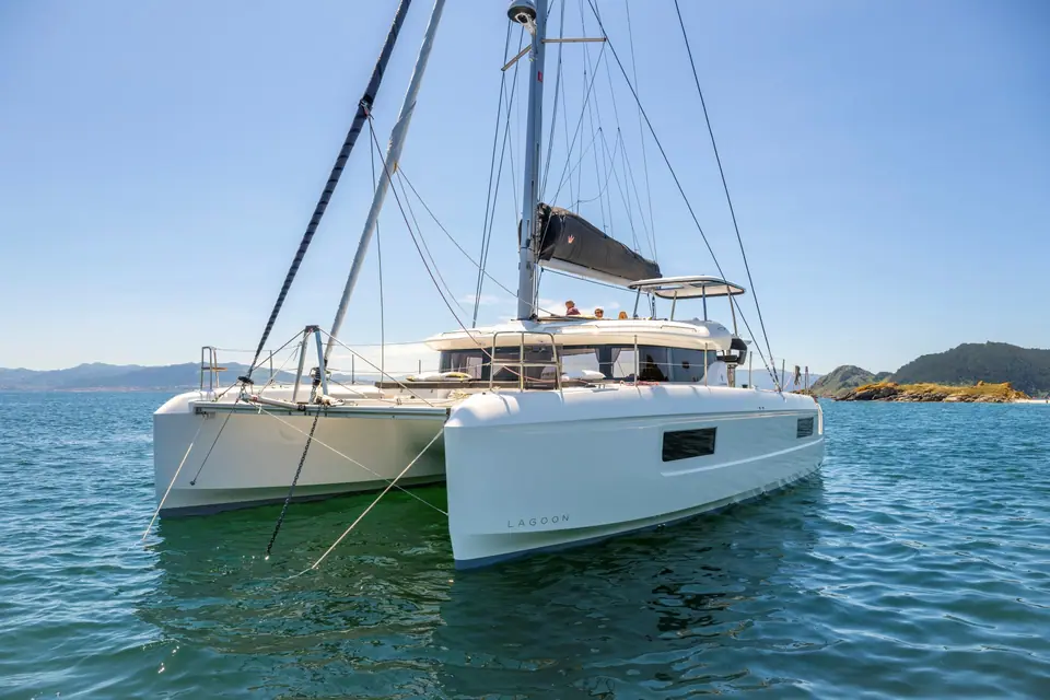 Lagoon 43 at anchor in clear water seen from the bow quarter with its flybridge boom
