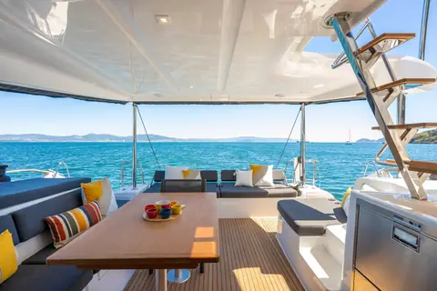 Lagoon 43 aft cockpit with a long dining table, cushioned benches and flybridge stairs