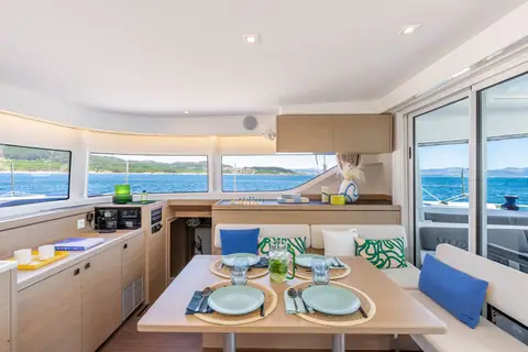 Lagoon 43 saloon with a set dining table, galley counter and wraparound windows