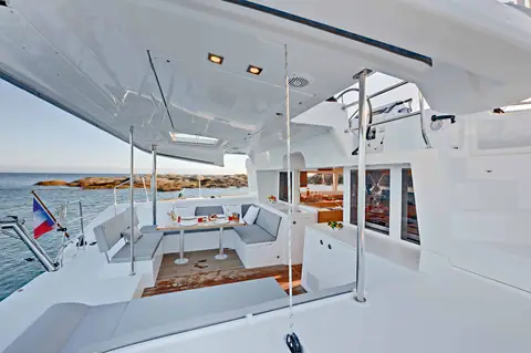Lagoon 450 aft cockpit with a dining table and settee under the flybridge overhang