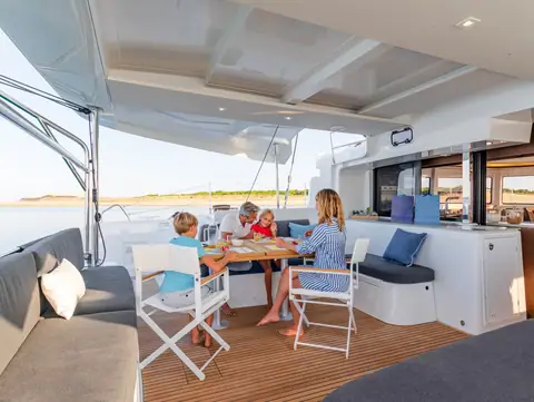 Lagoon 46 aft cockpit with a family at the teak table under the hardtop
