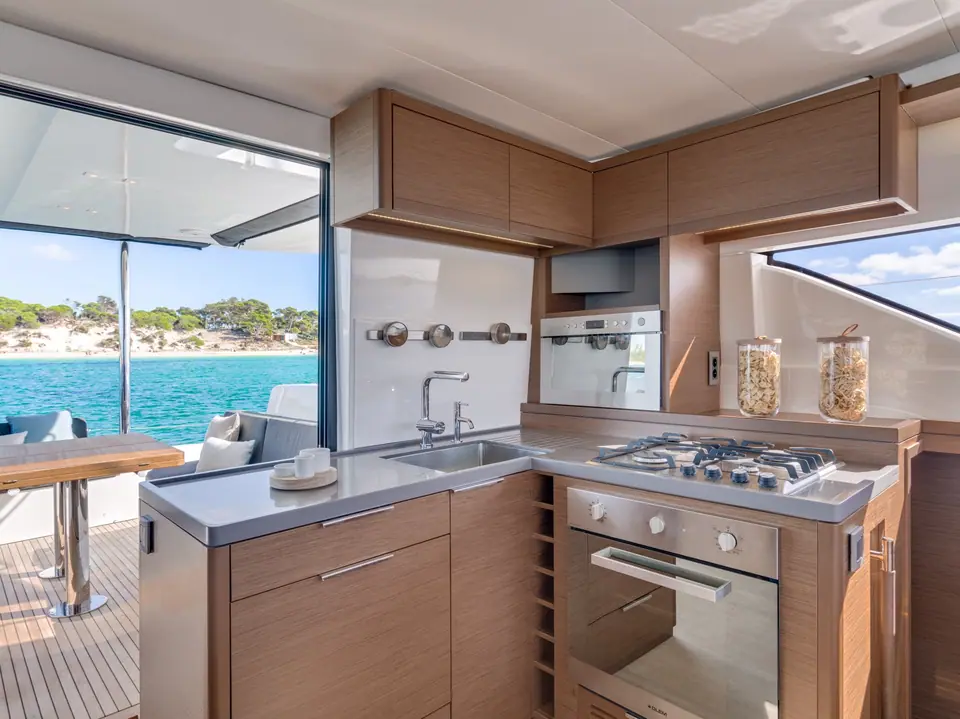 Lagoon 50 galley with wood cabinets, cooktop and oven beside the open cockpit door