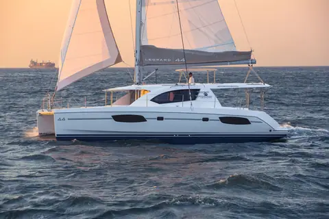 Leopard 44 sailing in profile at dusk showing its hull ports and hardtop bimini