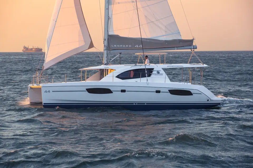Leopard 44 sailing in profile at dusk showing its hull ports and hardtop bimini