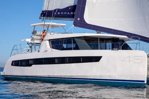Leopard 45 seen close from the bow quarter with the 45 logo on its hull and crew on the flybridge
