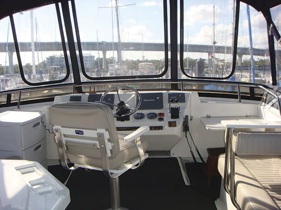 Enclosed flybridge helm of a Mainship 430 Trawler with a pedestal helm chair