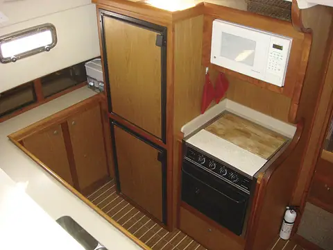 Galley down in a Mainship 430 Trawler with a stove, microwave and tall refrigerator