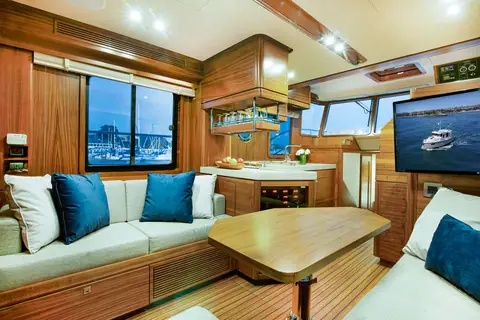 Nordhavn 41 salon with a U shaped settee, teak table and the galley forward