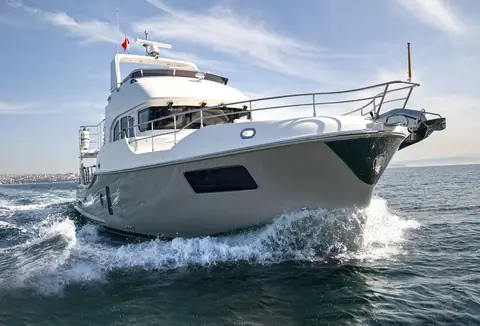 Nordhavn 51 bow throwing spray as it runs past the camera