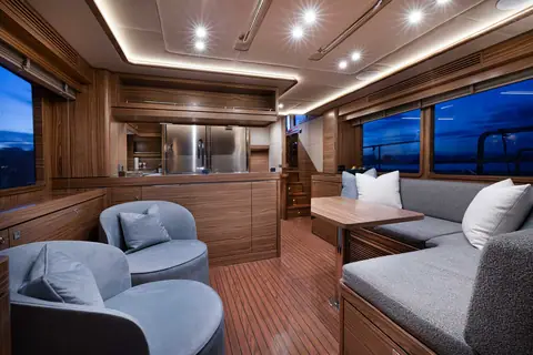 Nordhavn 51 salon with an L shaped settee, two club chairs and walnut joinery