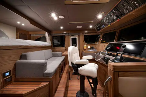 Nordhavn 51 pilothouse with helm chair, wheel and a settee berth behind