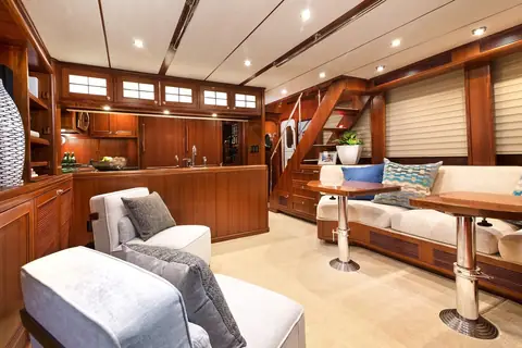 Nordhavn 63 salon with a settee, pedestal tables and the stairs to the pilothouse
