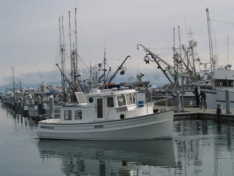 Nordic Tug 26 idling through a marina past commercial fishing boats