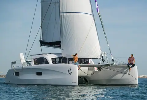 Outremer 45 sailing toward the camera with crew on the bow and helm stations