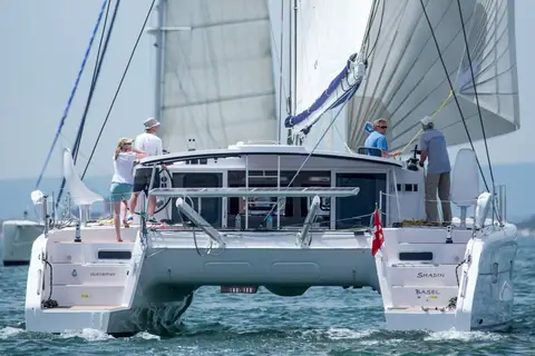 Outremer 45 seen from astern under sail with crew in the open cockpit