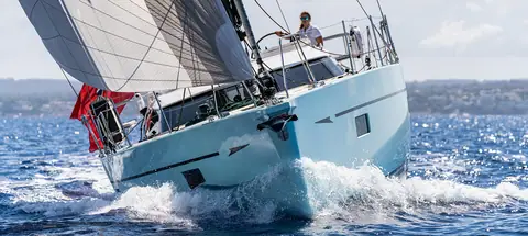 Oyster 495 heeled at speed from the bow quarter with the helmsman at the wheel