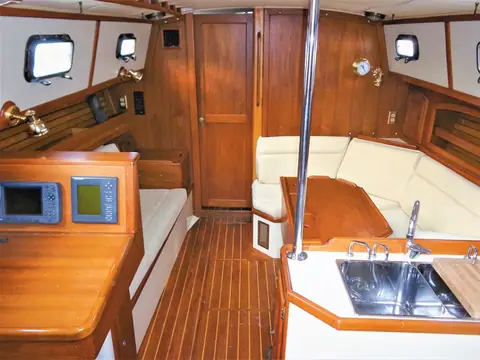 Pacific Seacraft 37 saloon with teak joinery, settees and nav station on a 1998 boat