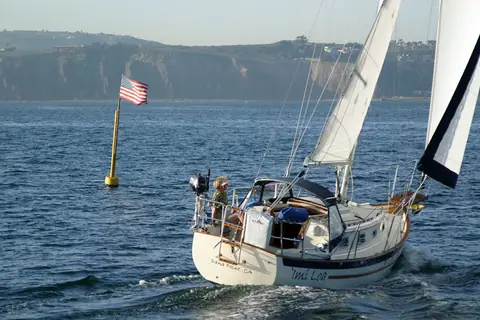 Pacific Seacraft Dana 24 sailing past a buoy seen from the stern quarter