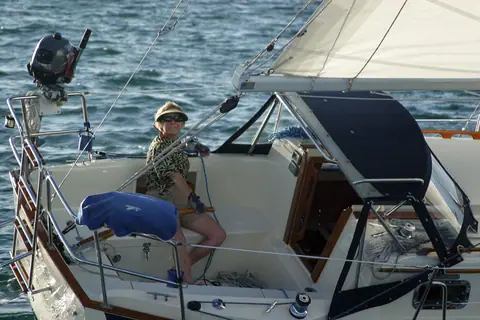 Pacific Seacraft Dana 24 cockpit and dodger with a sailor at the helm