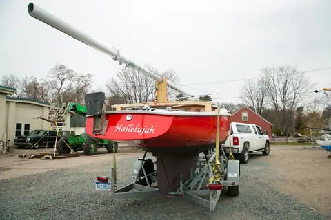 Restored Pearson Ensign with a red hull on its trailer showing the full keel