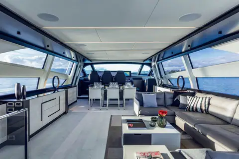 Pershing 9X main salon with sofas, dining area and helm forward