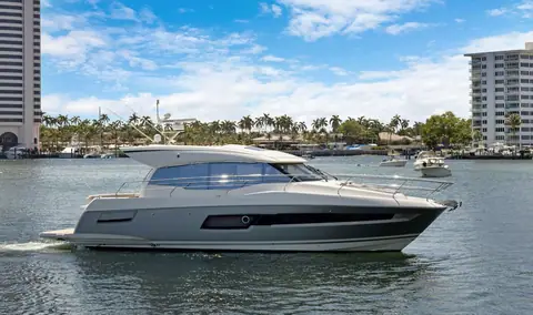 Prestige 460S hardtop coupe with a gray hull cruising in profile past a palm lined waterfront