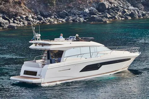 Prestige 520 at rest near a rocky coast showing the side deck, cockpit and flybridge