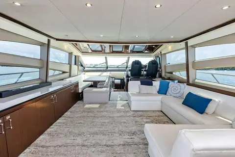 Princess 78 Motor Yacht main saloon with white sofas, dining table and helm seats forward